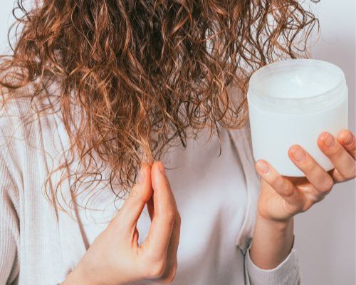 femme applicant produits sur cheveux bouclés 